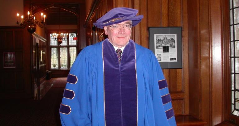 Hugh Gordon smiling at camera wearing academic regalia.