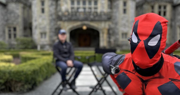 Deadpool leans into the frame with President Philip Steenkamp and Hatley Castle in the background.