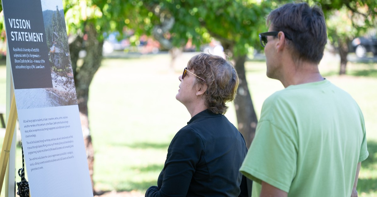 A couple is standing in an apple orchard reading a sign that says: Vision Statement