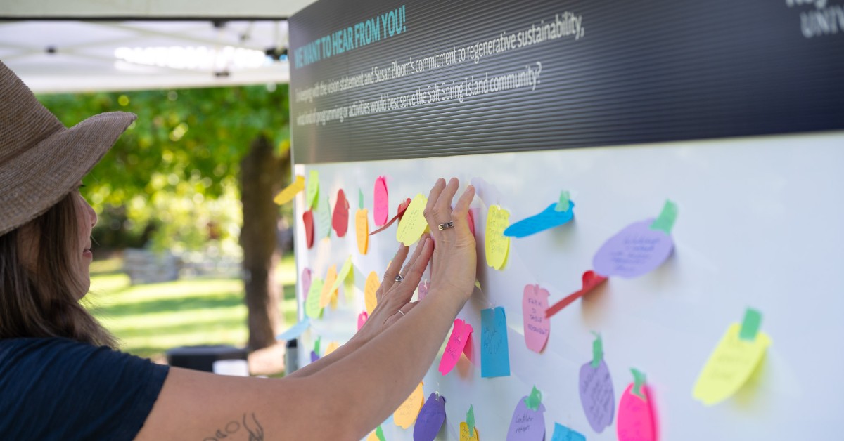 Woman adding a suggestion to an ideas board that has been placed in an apple orchard.