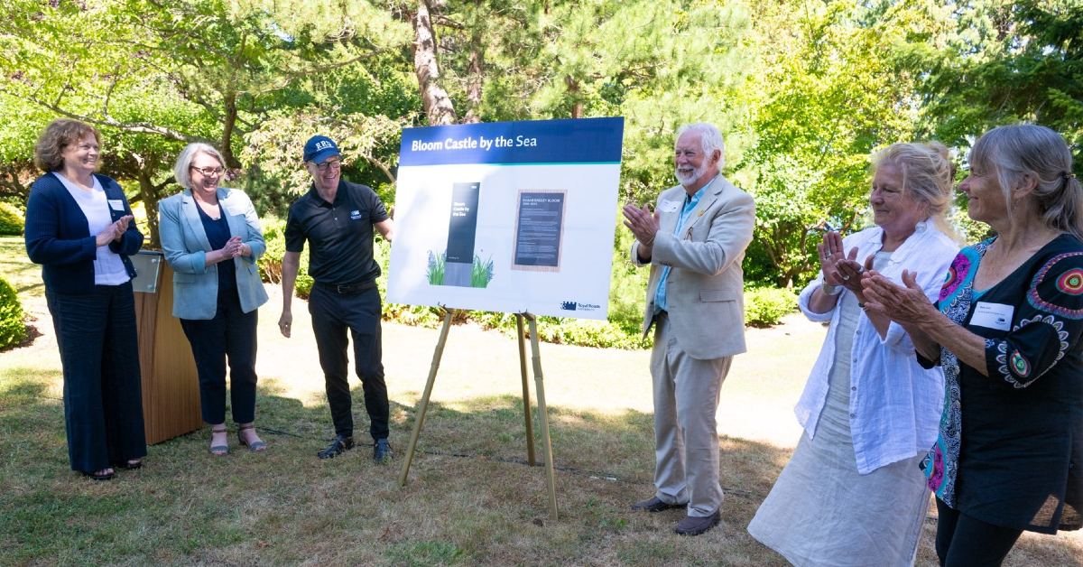 Veronica Thompson, Philip Steenkamp and guests clap as they unveil a sign reading Bloom Castle by the Sea