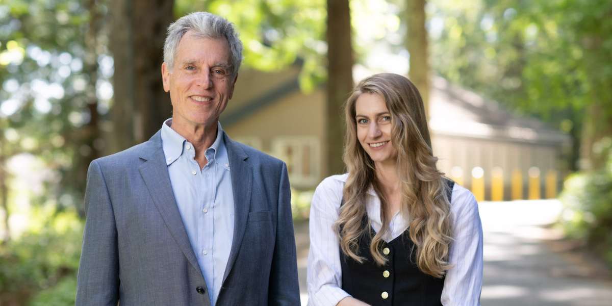 Two members of the Cascade Institute pose for a photo in a forested area on the RRU campus