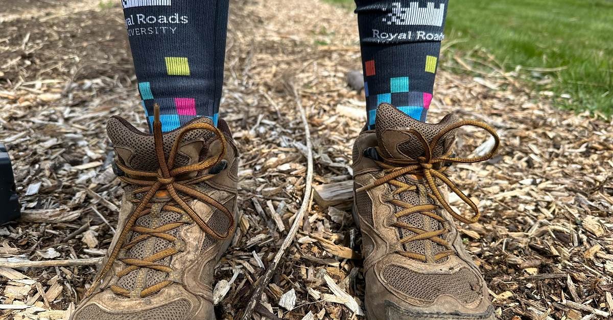 Hiking boots with Royal Roads branded socks standing on mulch.