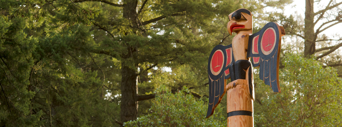 Totem pole looks over a lush forest on the Royal Roads University campus