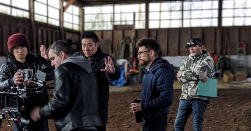 Filmmaker, Arnold Lim, gesturing with open hands while standing on set of All-in Madonna.