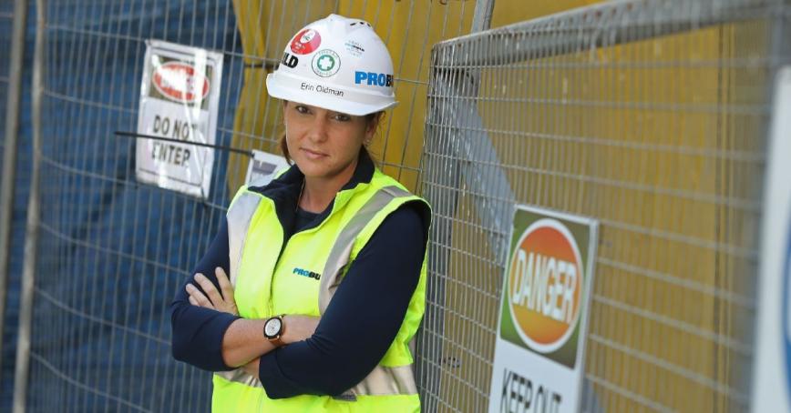 Erin Oldman standing with her arms crossed in a construction uniform