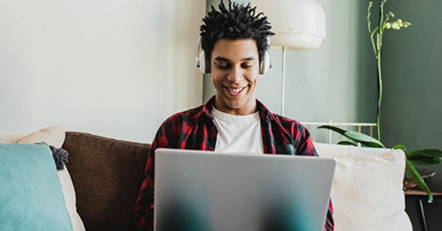 Person sitting on a couch with their laptop cmiling