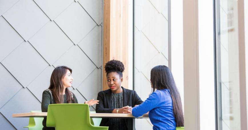 Three people sitting at a table talking