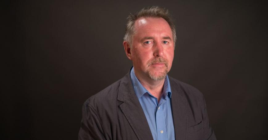 Prof. Ken Christie poses in a head-and-shoulders portriat against a black background.