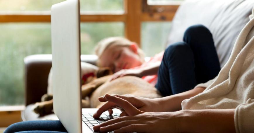lady on laptop with child sleeping on couch