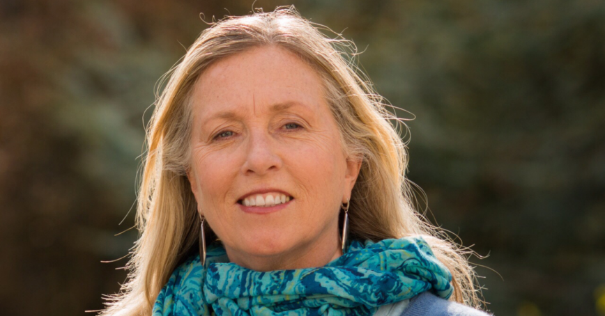 Prof. Robin Cox headshot standing with forest behind her.