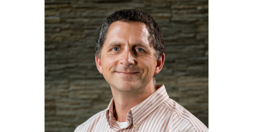 Head shot of Eugene Thomlinson with a stone wall behind him