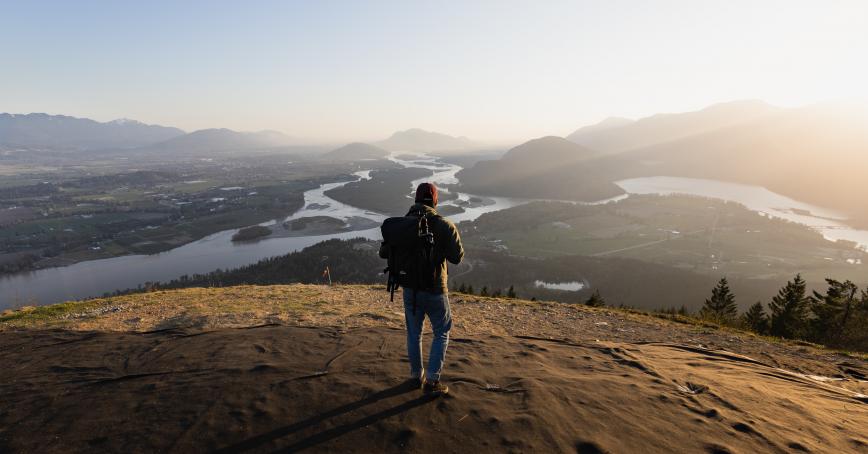 student walking on a hill and looking at a river