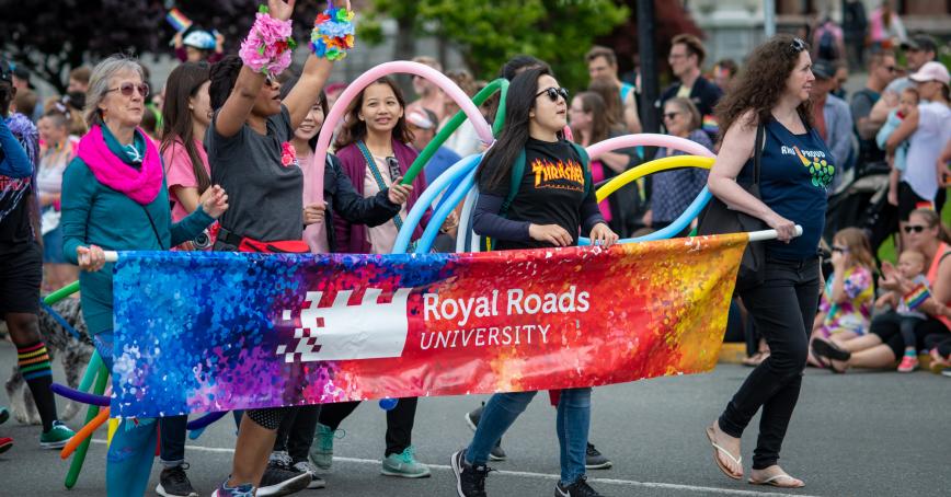 Members of the RRU community holding a Pride-themed RRU banner and walking in the Victoria pride parade.