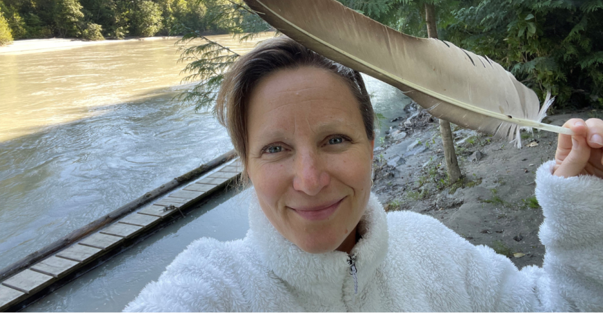 Veronica Woodruff poses with a feather near a river.