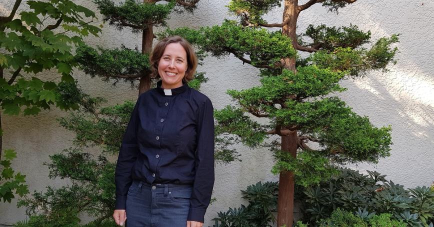 MBA grad Alecia Greenfield stands in front of some trees.