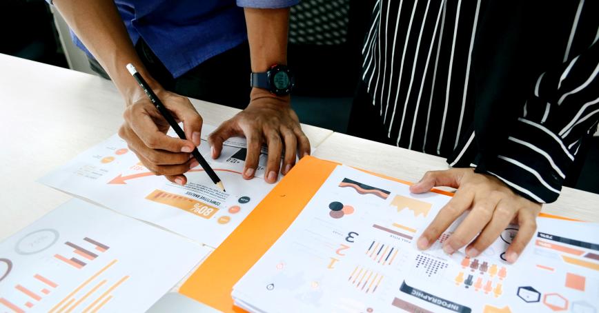 Two people working on data and books on a table