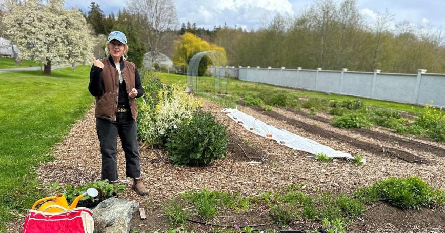 Woman standing in garden next to collard plants.