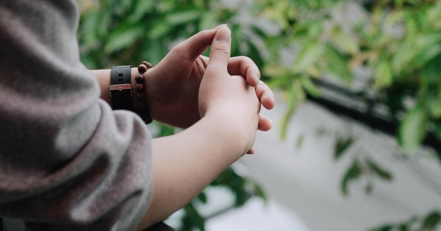 image of a person with hands clasped together as though they are thinking and looking over a window sill