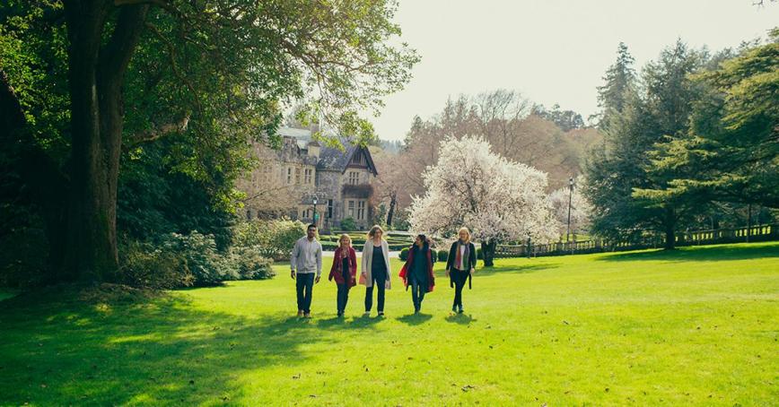 A line of RRU staff walk side-by-side on the greens of campus