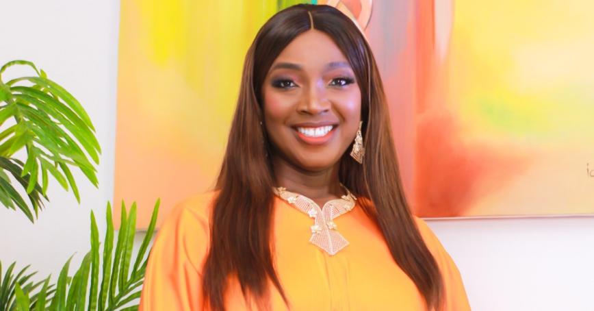 Anuli Ausbeth-Ajagu smiles in front of an orange and yellow painting