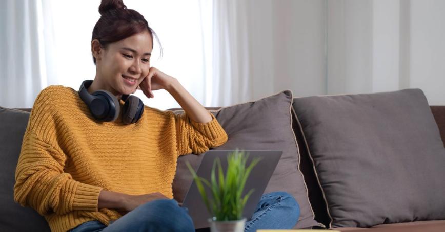 A young woman smiles while looking at her computer.