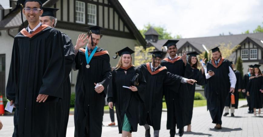 ! group of graduates celebrate as they process