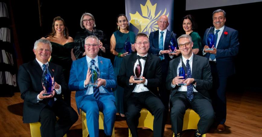 Awardees pose in a group, holding their awards.