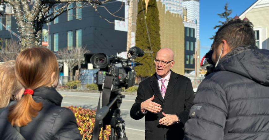 Philip Steenkamp stands across the street from RRU Langford campus speaking to reporters