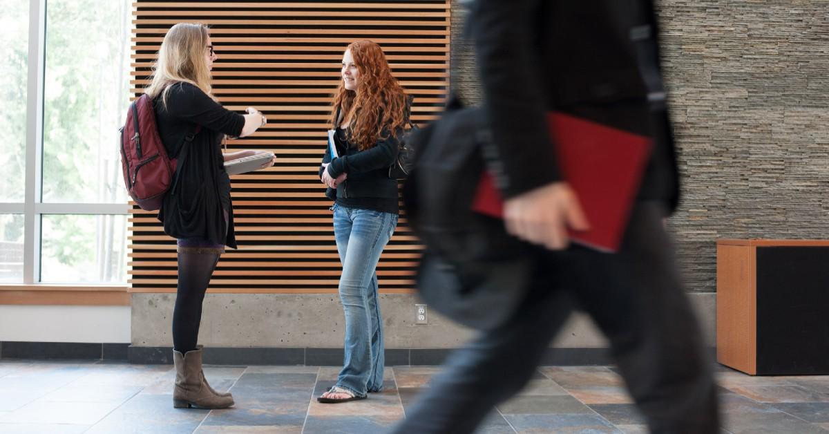 Students talking in a hallway while others pass by