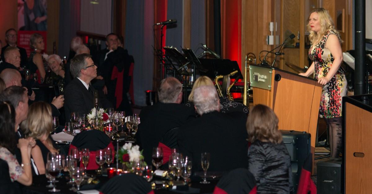 Tanya Patullo speaking at a podium in front of a seated crowd