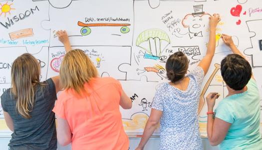 four-people-facing-a-whiteboard-and-writing-on-it