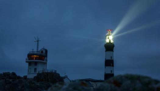 Lighthouse with it's light shinning in the night sky.