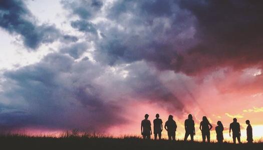 People silhouetted standing watching sunset