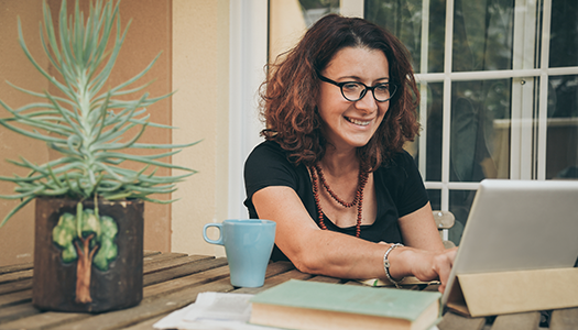 Person on laptop beside houseplant and coffee mug