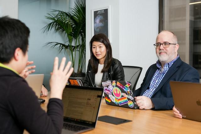 Three people meeting in a boardroom.