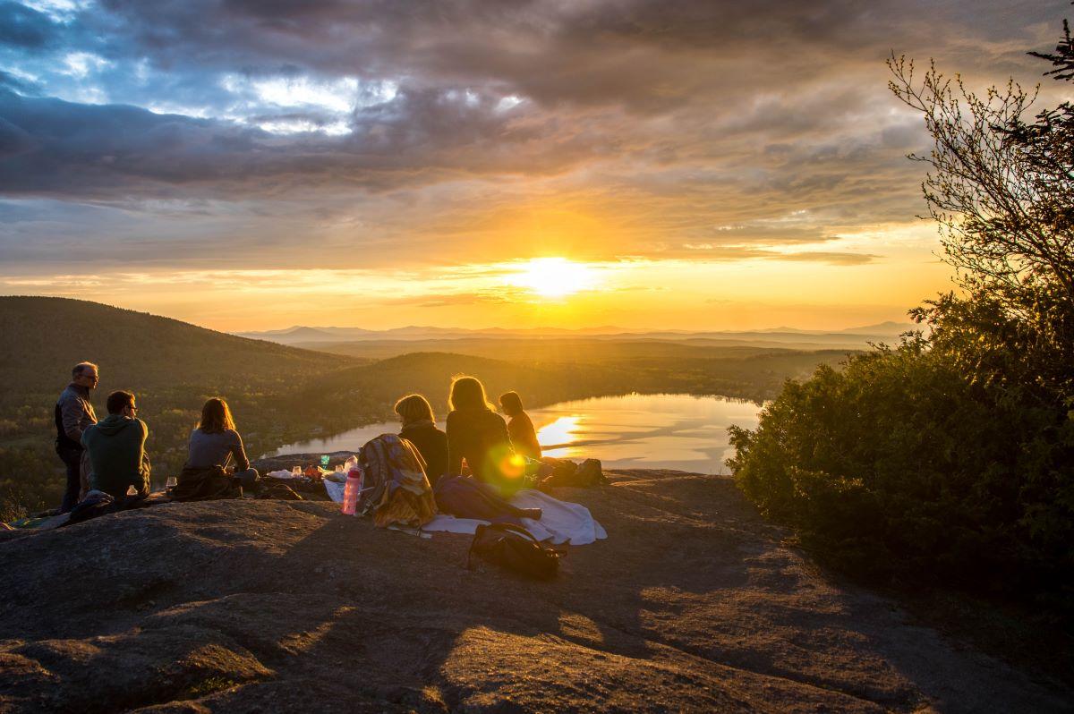 Small group enjoying viewpoint of lake at sunset.