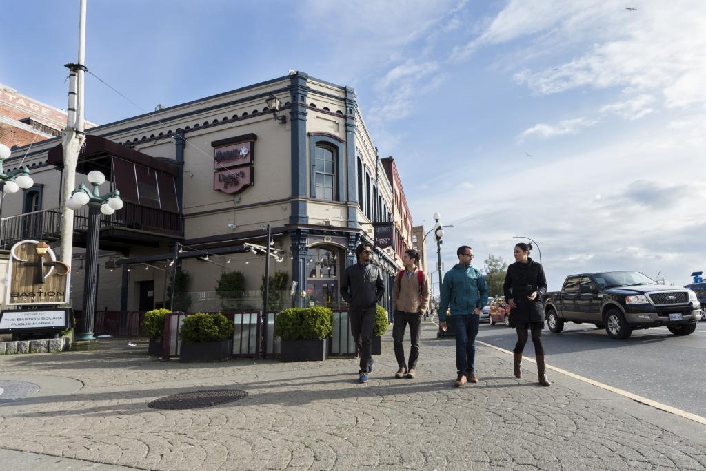 Four students walk together in front of a building in Victoria's Bastion Square area.