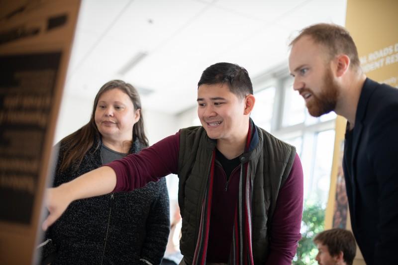 Student-pointing-at-display-board-with-others-watching