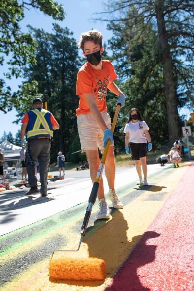 Student painting a Pride crosswalk on RRU campus