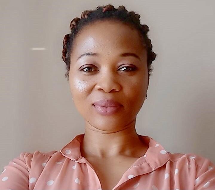 a woman wearing a pink blouse smiles for camera