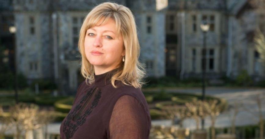 A head shot of a woman standing in front of a stone castle.