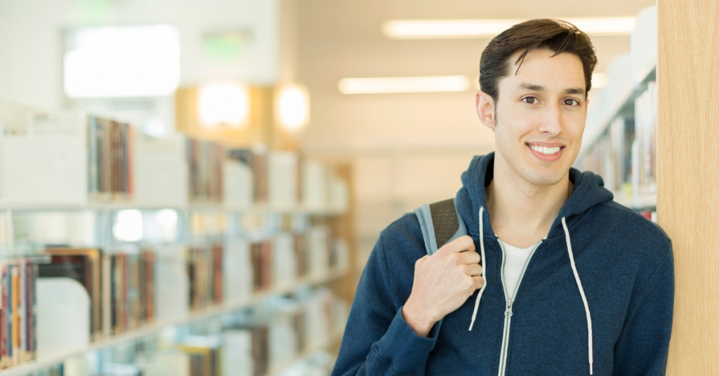 Leo Chavez leans against a wall in the brightly lit library.