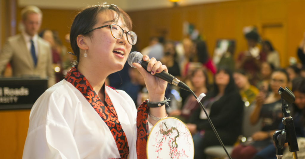 A student wearing traditional cultural fashion and singing at the Royal Roads International Showcase.