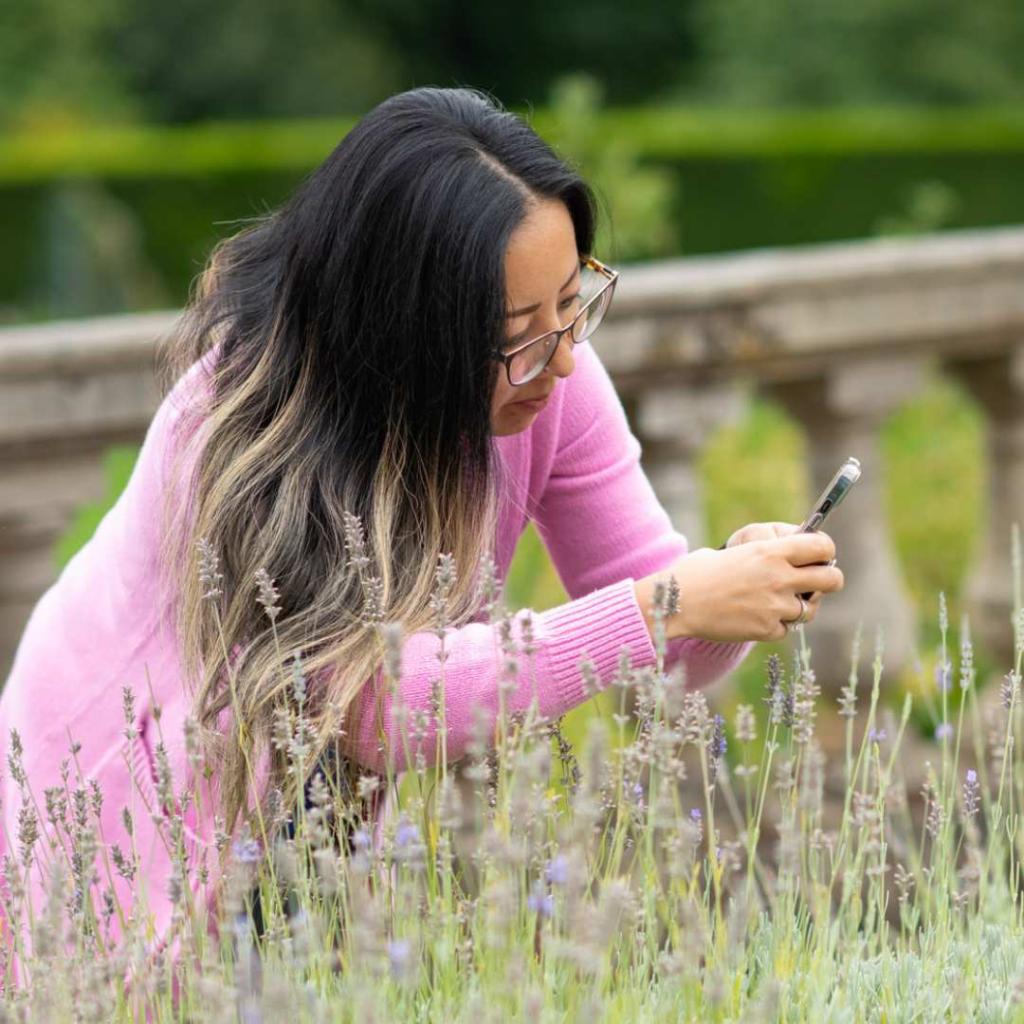 A Royal Roads University alumni takes a photo of blossoming flowers on campus.