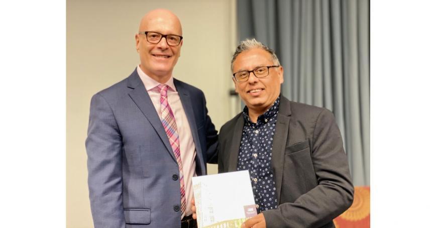 Alberto Callo poses with RRU President Philip Steenkamp while holding a plaque. Both are smiling.