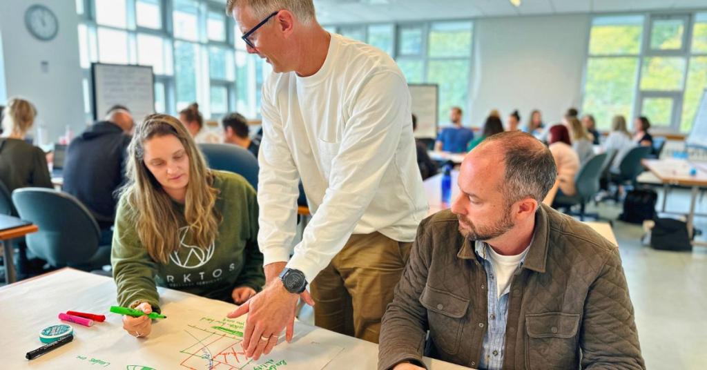 Three MBA students brainstorm on a piece of poster paper