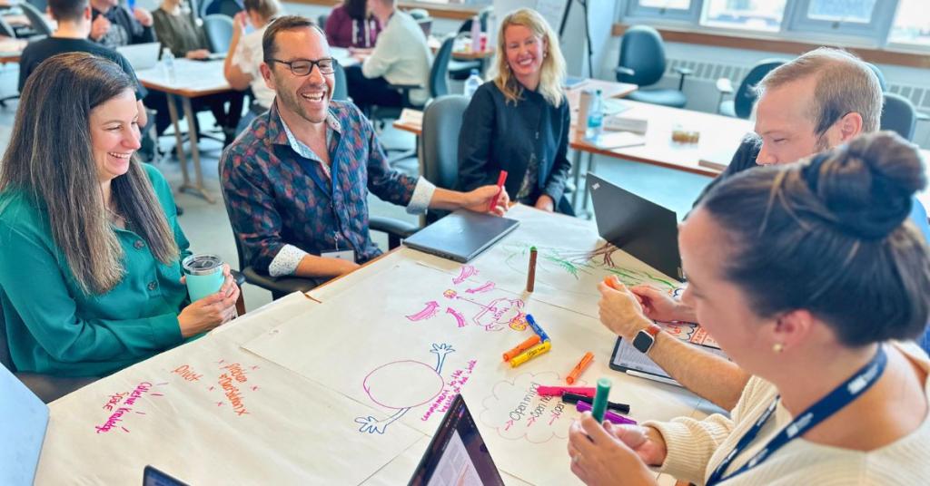 A group of students laughs at a table project