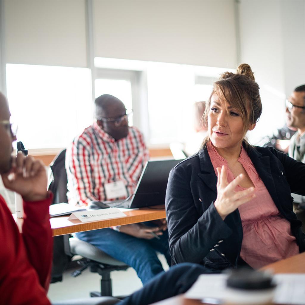 A DBA student at RRU sits in a classroom surrounded by peers, engaging in conversation