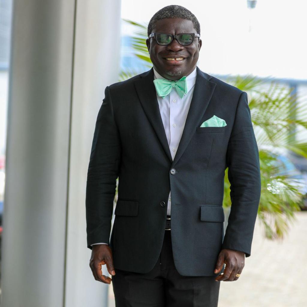 A smiling man in a suit and mint green bow tie